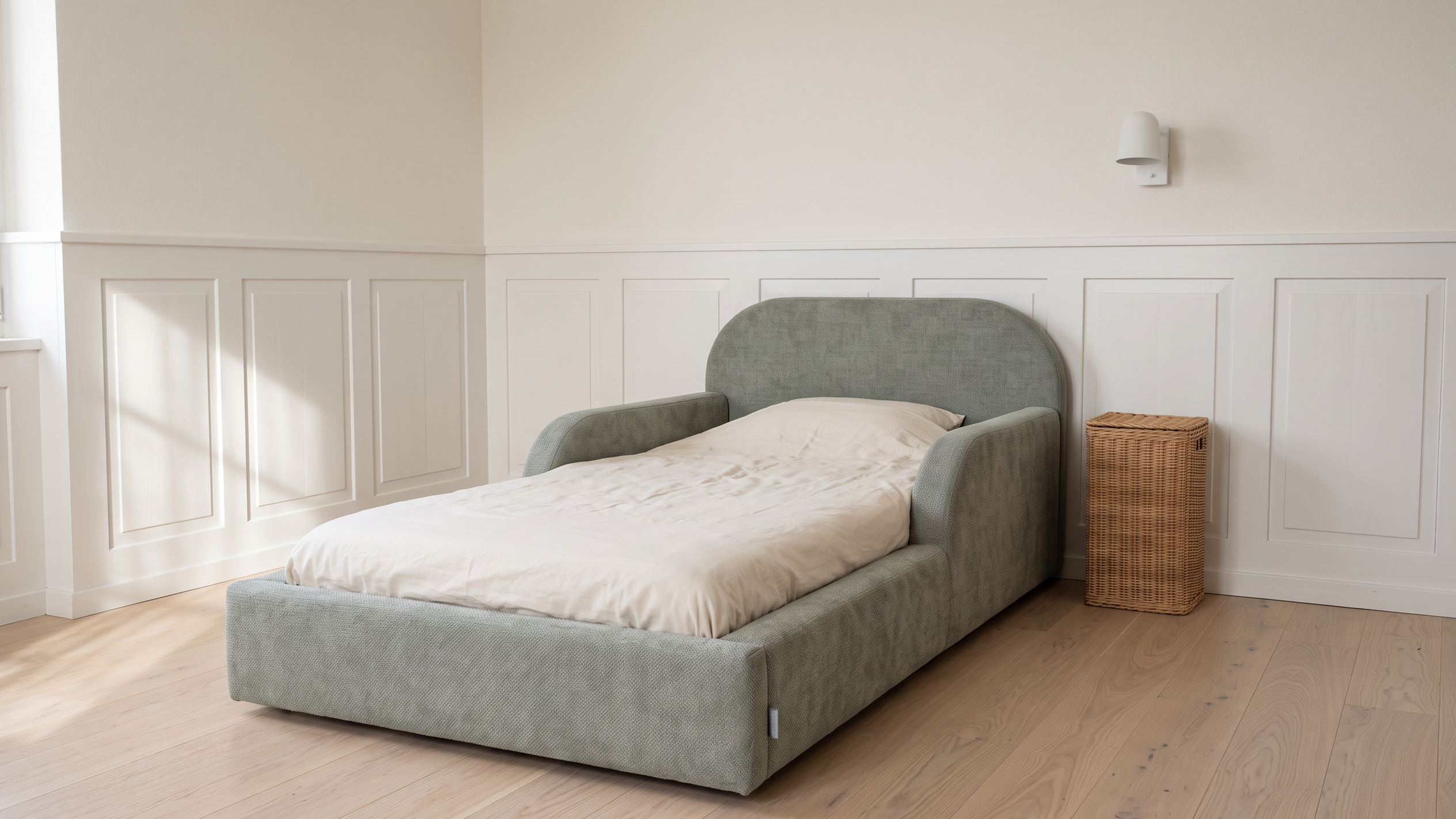 Gepolstertes Mila Cloud Kinderbett in Salbeigrau in einem hellen Kinderzimmer mit weisser Holztäfelung