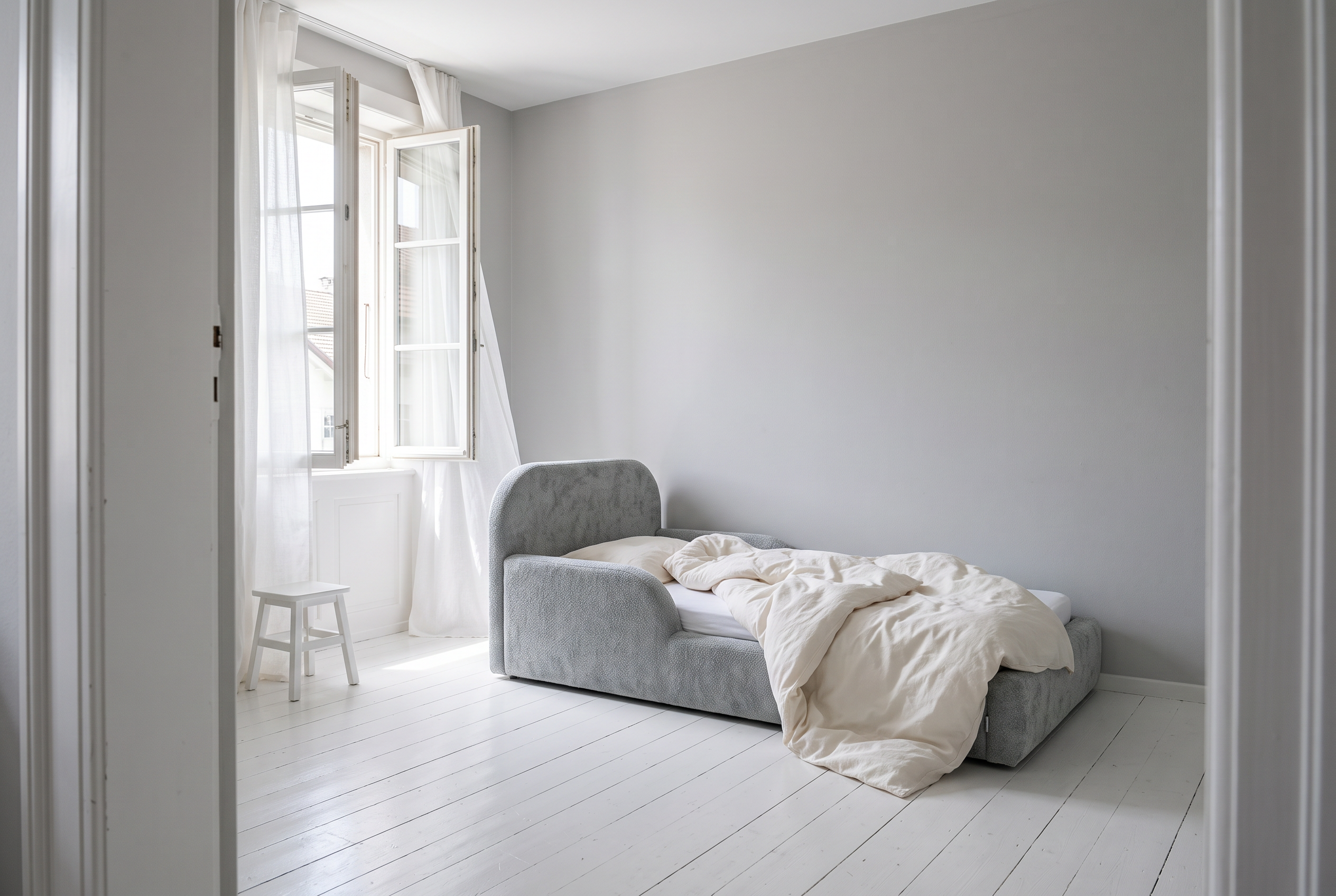 Kinderzimmer mit weit geoeffnetem Fenster und Mila Cloud Kinderbett in Nebelgrau, Bettdecke zum Auslueften zurueckgeschlagen